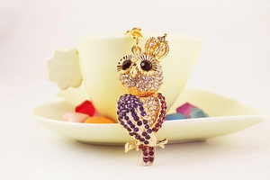 Détail du porte-clés chouette doré avec strass violets et roses sur une tasse