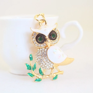 Enamel owl keychain with white rhinestones and green eyes on a metallic branch