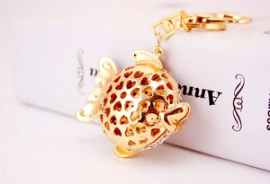 Detailed close-up of a gold tropical fish keychain with heart cutouts and white rhinestones
