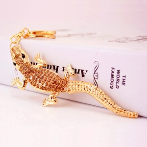 Golden lizard keychain with amber rhinestones and lobster clasp on white book