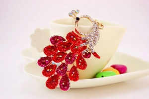 Close-up of colorful rhinestone peacock keychain hanging on a white heart-shaped ceramic cup