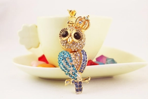 Détail du porte-clés hibou avec strass bleus étincelants et accent de couronne dorée