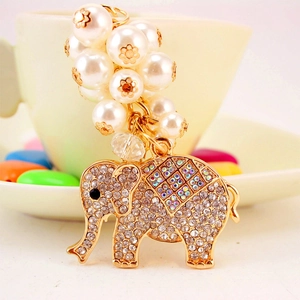 Elegant elephant keychain with pearls and crystals on a white ceramic cup background