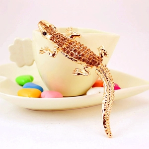 Sparkling rhinestone gecko keychain accessory in gold plating on a cup edge