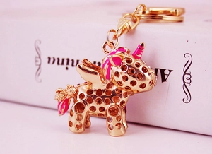 Close-up of golden unicorn keychain with pink enamel details and hollow design