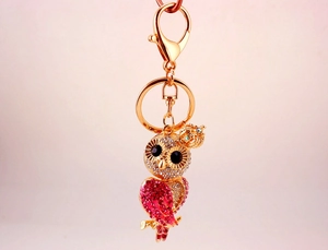 Détail du porte-clés hibou doré orné de strass roses et blancs et petite couronne