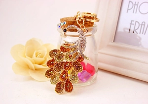 Detail of golden peacock keychain with vibrant amber rhinestones and crystal accents