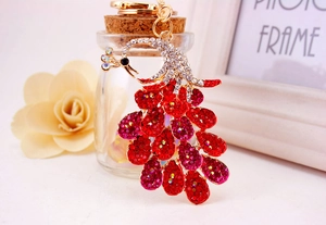 Detailed close-up of a peacock keychain with red rhinestones and gold metal frame