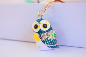 Close-up of golden owl keychain with colorful enamel inlay and sparkling crystal wings
