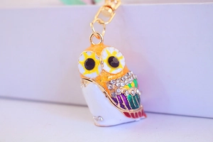 Close-up of owl keychain with colorful enamel textures and white rhinestone details