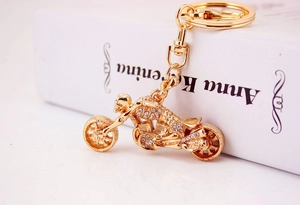 Detail of a golden motorcycle keychain with white rhinestones leaning on a white book