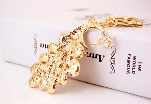 Detailed back view of a golden peacock keychain with fine texture and metal ring