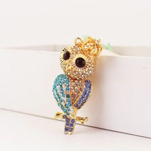 Porte-clés hibou doré avec strass colorés et couronne sur une boîte blanche
