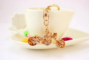 Detail of golden motorcycle keychain with sparkling rhinestones on a ceramic cup