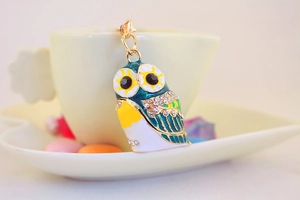 Macro view of a colorful enamel owl keychain with rhinestones hanging on a coffee cup