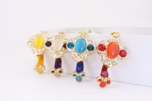 Detail of four golden key-shaped pendants with colorful gemstones and diamond accents