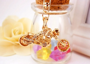 Close-up of golden motorcycle skull keychain with crystal rhinestones on a decorative base