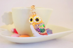 Macro shot of owl keychain with colorful enamel and sparkling rhinestones on golden alloy