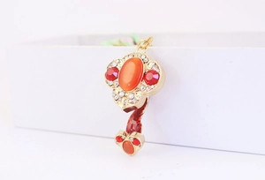 Detail view of golden ruyi keychain featuring orange cat-eye stone and red rhinestones