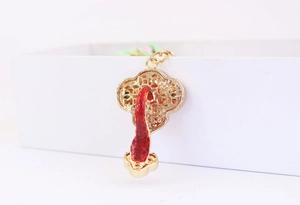 Detail of a golden Chinese Ruyi keychain with hollow pattern and red decorative element