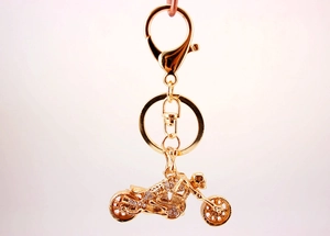 Detailed view of motorcycle keychain with shiny crystals and golden metal finish