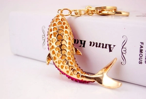 Detailed macro of gold dolphin keychain featuring pink rhinestones and heart cutouts