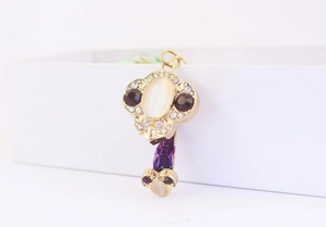 Macro detail of key-shaped keychain with cat eye stone and purple textured handle