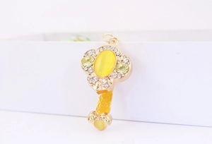 Macro detail of a golden key pendant with a large yellow cat-eye stone and white crystals