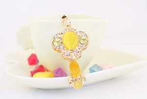Detail of Ruyi jade keychain with yellow stones and crystals on a white ceramic cup
