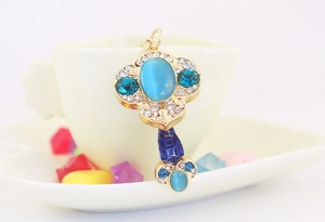 Detail of a golden pendant with a blue cat-eye stone and rhinestones on a coffee cup edge