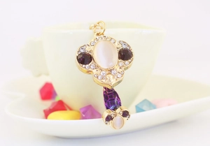 Detail of Ruyi gold keychain with white opal, purple crystal and sparkling rhinestones
