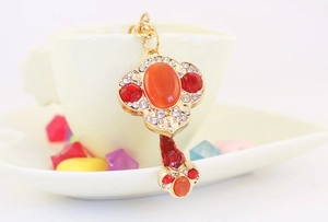 Detailed close-up of golden Ruyi keychain with orange cat-eye stone and red rhinestones