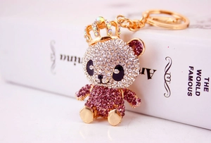 Detail eines lila-silbernen Strass-Panda-Schlüsselanhängers mit goldener Krone auf Buch
