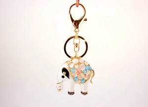 Detailed close-up of a gold elephant keychain with opal beads and white enamel finish