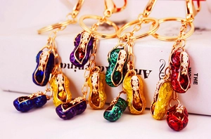 Detailed view of colorful enamel peanut keychains with sparkling crystals on white book