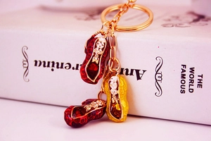 Detail shot of three enamel peanut charms on a golden metal keychain with red gemstones