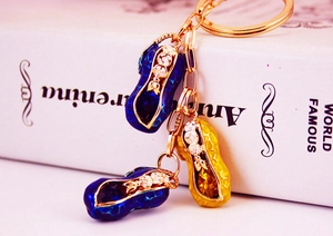 Detailed close-up of blue and yellow peanut charms on a metal keychain with floral patterns
