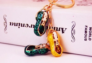 Detailed macro view of enamel peanut keychains with yellow and green gemstones in gold finish