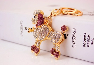 Macro detail of poodle keychain with purple and white crystals on golden base