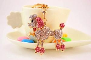 Detail of a gold poodle keychain with white and pink rhinestones on a coffee cup
