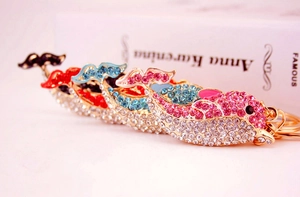 Close-up of golden dolphin keychains with colorful rhinestones on a book background