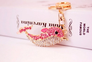 Detailed macro shot of pink rhinestone dolphin keychain on a golden alloy metal base