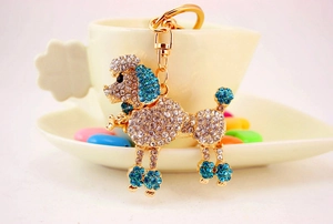 Detail of a sparkling poodle keychain with blue and clear crystals on a golden alloy frame