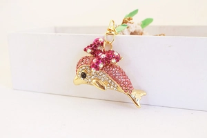 Macro detail of golden rhinestone dolphin keychain with pink crystal bow and lobster clasp