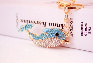 Close-up of dolphin keychain featuring blue rhinestones and gold-plated metal clasp
