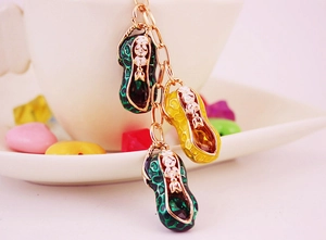 Close-up of green and yellow peanut pendants with vintage patterns on a golden chain