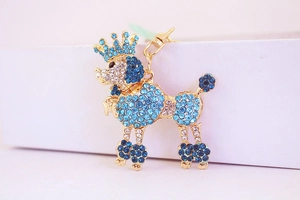 Close-up of a poodle keychain with blue rhinestones, crown detail, and gold lobster clasp