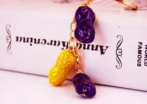 Close-up of peanut keychain with yellow and purple charms on golden chain