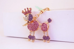 Macro detail of royal purple crystal poodle keychain with golden crown and rhinestones