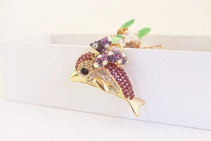 Detail of dolphin keychain featuring purple rhinestones and a bow on a display box